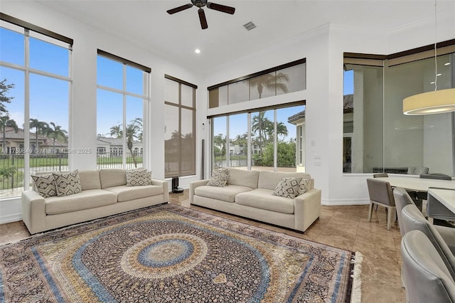 living room featuring visible vents, plenty of natural light, ceiling fan, and a towering ceiling