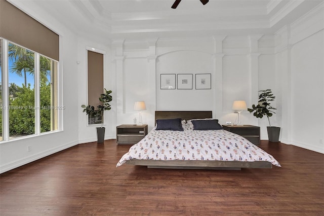 bedroom featuring wood finished floors, a high ceiling, baseboards, and ornamental molding