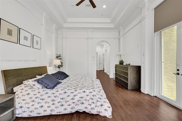 bedroom with dark wood-style floors, a tray ceiling, arched walkways, ceiling fan, and ornamental molding