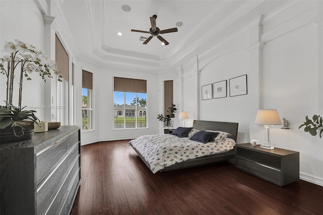 bedroom featuring ceiling fan, baseboards, ornamental molding, wood finished floors, and a raised ceiling