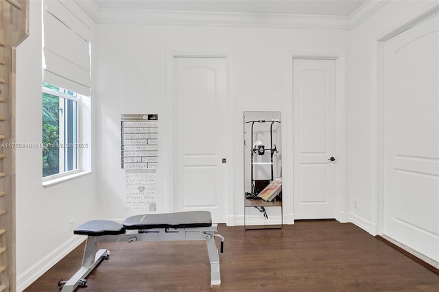 workout area featuring dark wood-type flooring, baseboards, and ornamental molding