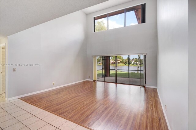 221 NW 201st Ave, Pembroke Pines, FL 33029 - unfurnished living room with baseboards, a water view, a towering ceiling, and light wood-style flooring