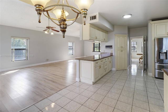 kitchen with visible vents, baseboards, open floor plan, ceiling fan with notable chandelier, and stainless steel fridge