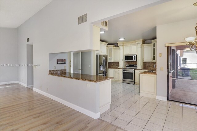 221 NW 201st Ave, Pembroke Pines, FL 33029 - kitchen with stainless steel appliances, cream cabinetry, decorative backsplash, a sink, and glass insert cabinets
