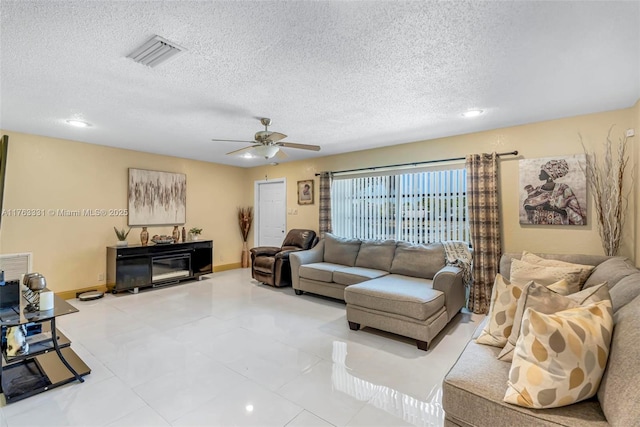 living room with baseboards, visible vents, a textured ceiling, and ceiling fan