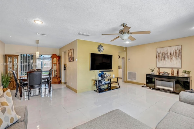 living area with tile patterned floors, visible vents, and a ceiling fan