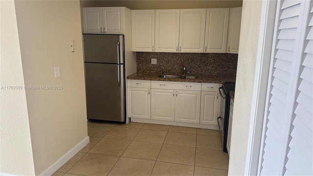 kitchen featuring a sink, electric range, white cabinetry, and freestanding refrigerator