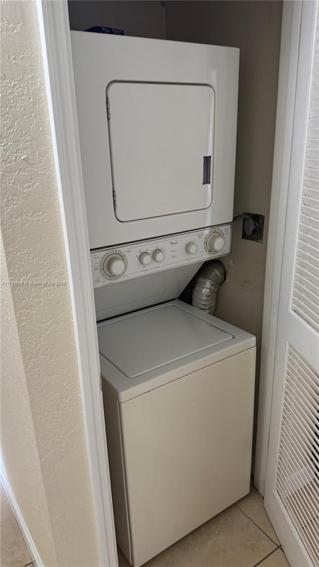 laundry area with light tile patterned flooring, laundry area, and stacked washer / dryer