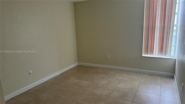 spare room with light tile patterned flooring and baseboards