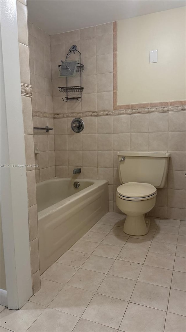 bathroom featuring tile patterned flooring, tile walls, toilet, and shower / tub combination