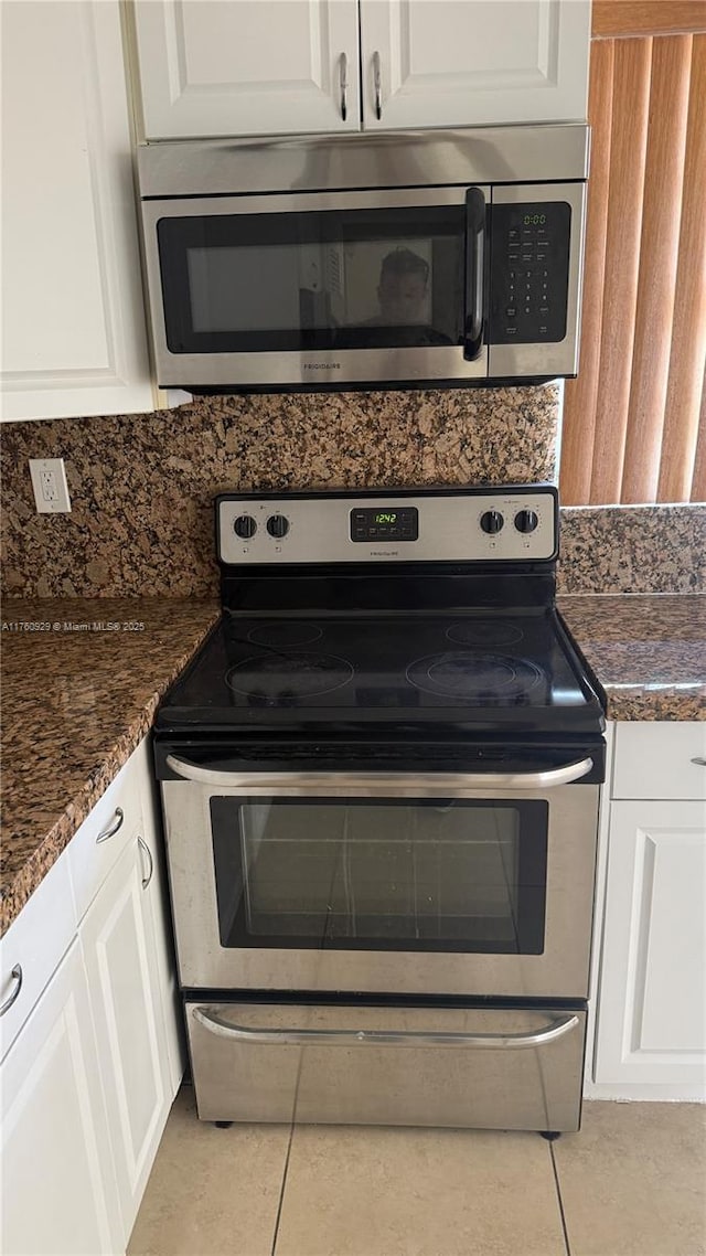 kitchen featuring light tile patterned floors, stainless steel appliances, white cabinets, and decorative backsplash