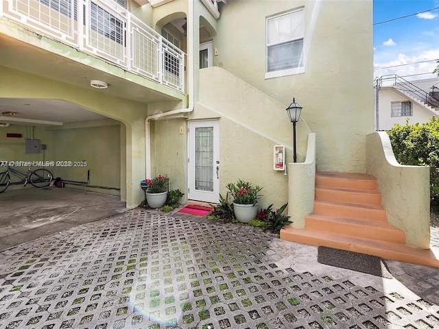 doorway to property with electric panel and stucco siding