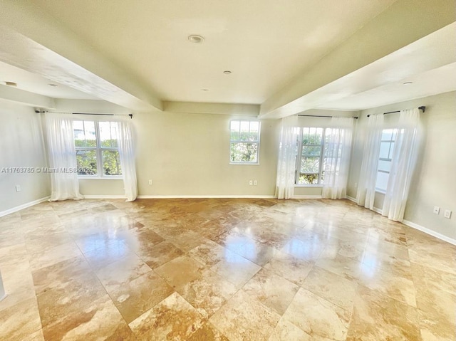 empty room with a healthy amount of sunlight and baseboards