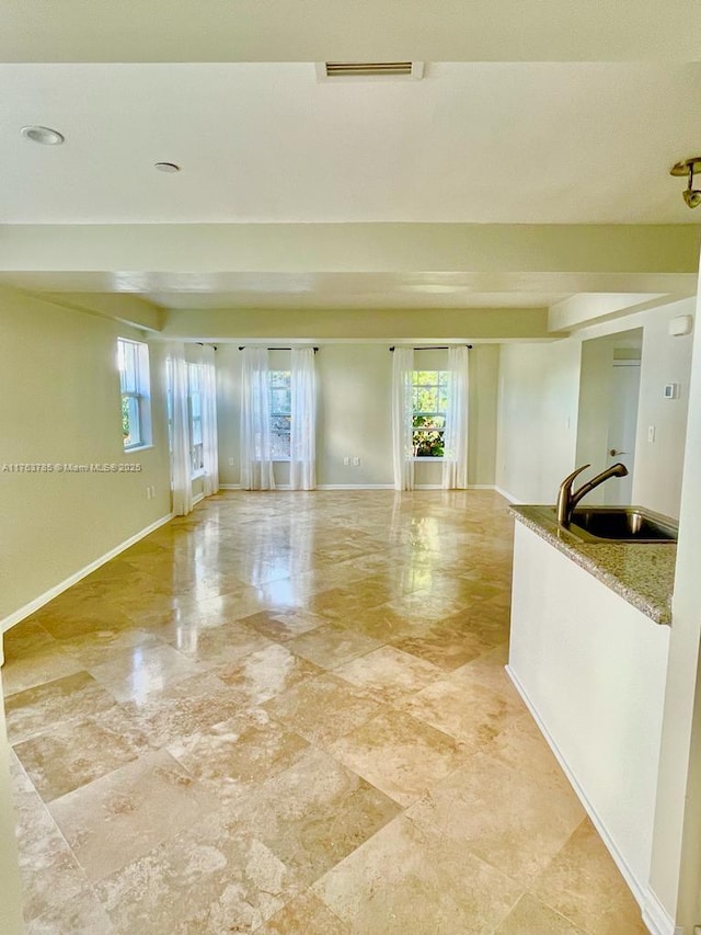 spare room featuring a sink, baseboards, and plenty of natural light