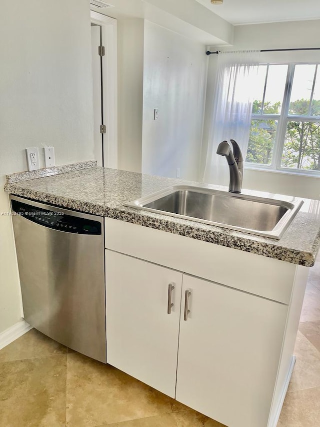 kitchen with stainless steel dishwasher, white cabinetry, and a sink