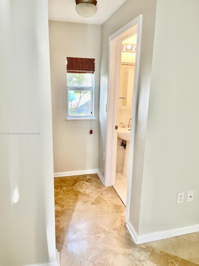 hall with a sink and baseboards