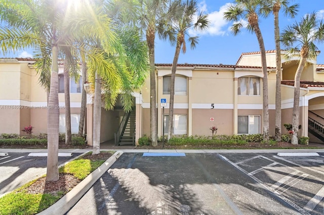 view of property featuring stairs and uncovered parking