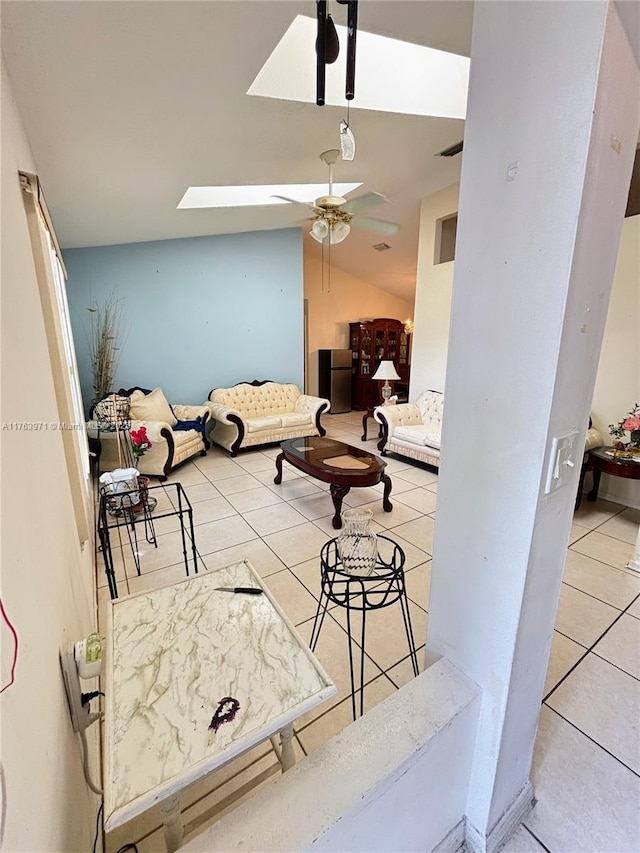 living room featuring tile patterned floors, vaulted ceiling with skylight, and ceiling fan