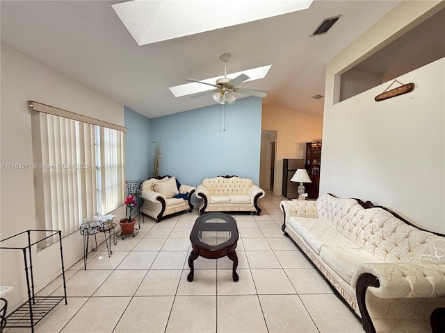 living room featuring vaulted ceiling with skylight, light tile patterned floors, a ceiling fan, and visible vents