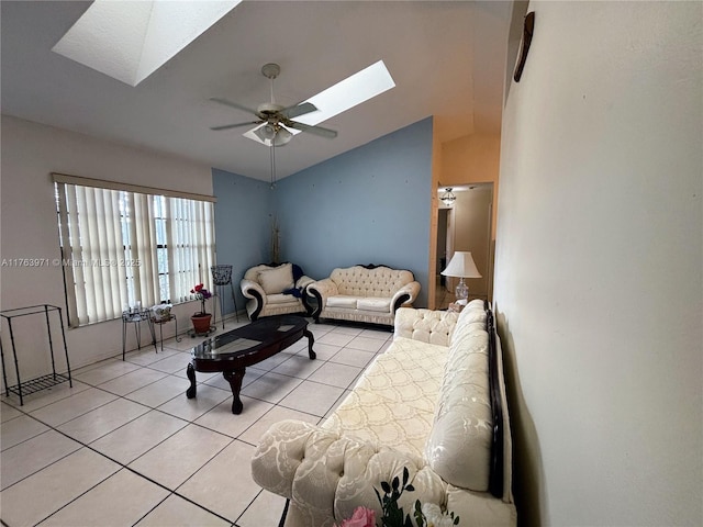 living room with vaulted ceiling with skylight, light tile patterned flooring, and a ceiling fan