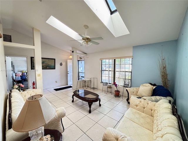 living room with vaulted ceiling with skylight, light tile patterned floors, and a ceiling fan