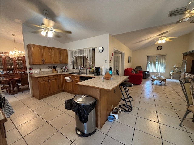 kitchen featuring tile countertops, visible vents, vaulted ceiling, and ceiling fan with notable chandelier