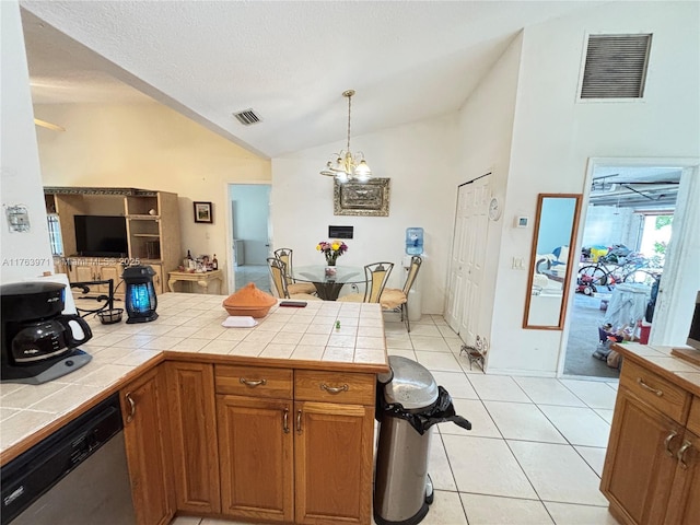 kitchen featuring tile counters, visible vents, vaulted ceiling, and stainless steel dishwasher