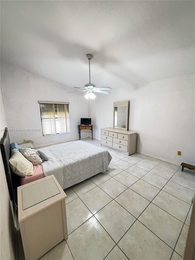 bedroom with vaulted ceiling, light tile patterned flooring, and a ceiling fan