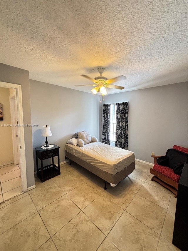 bedroom with light tile patterned floors, a ceiling fan, baseboards, and a textured ceiling