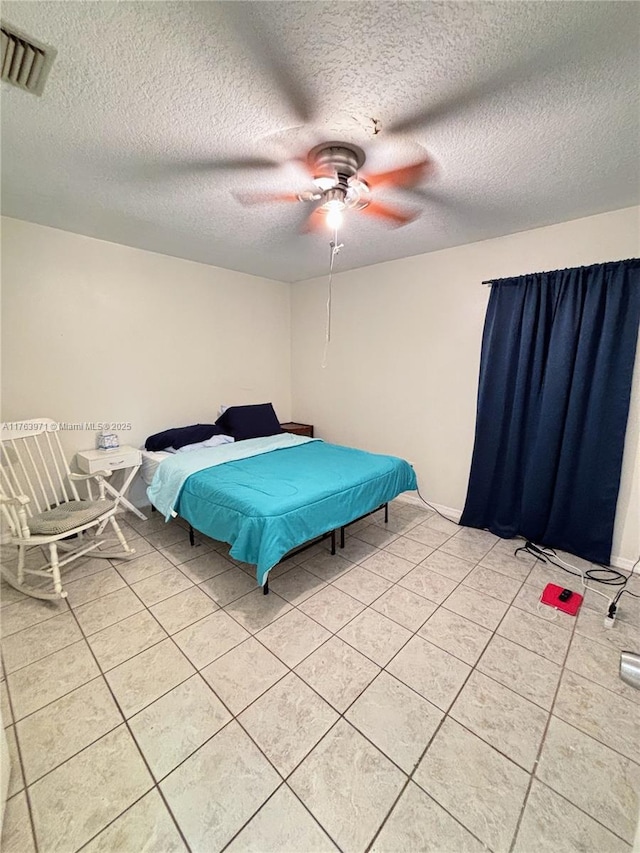 bedroom with ceiling fan, light tile patterned flooring, visible vents, and a textured ceiling