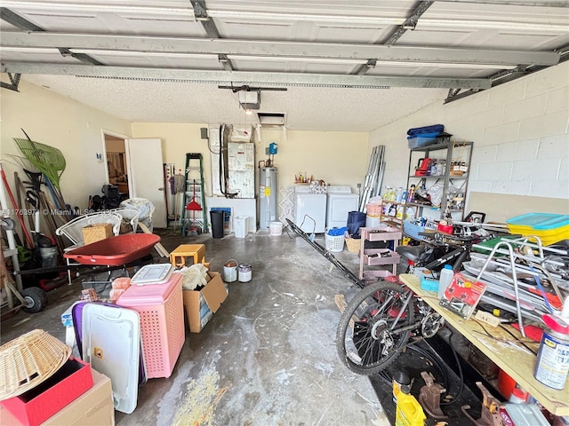 garage with washing machine and dryer, a garage door opener, electric water heater, and concrete block wall