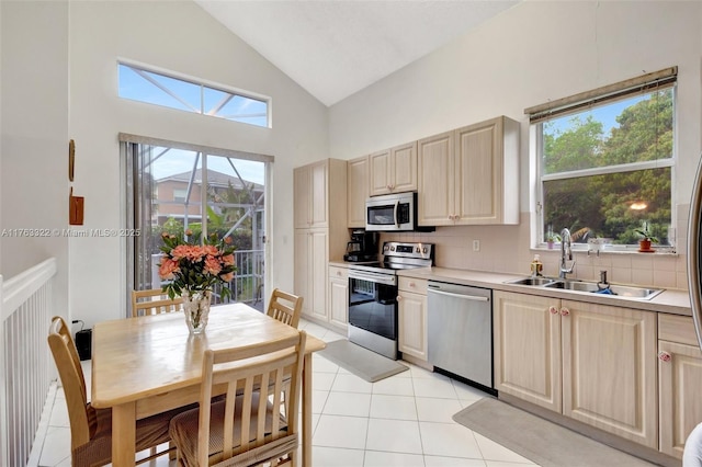 kitchen featuring tasteful backsplash, light countertops, light tile patterned floors, appliances with stainless steel finishes, and a sink