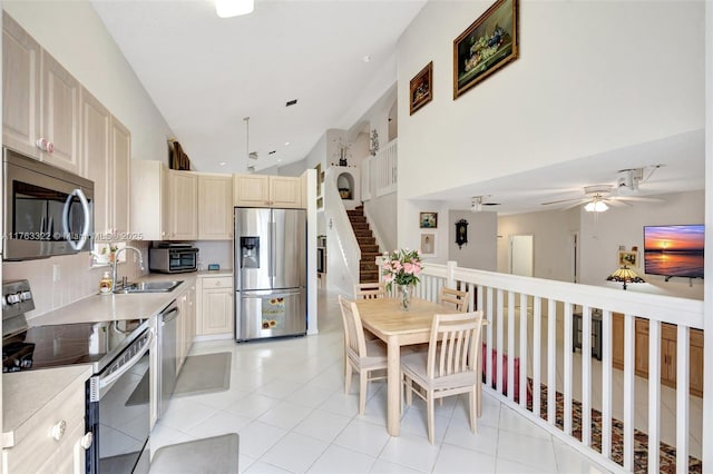 kitchen with light countertops, light tile patterned floors, appliances with stainless steel finishes, a ceiling fan, and a sink