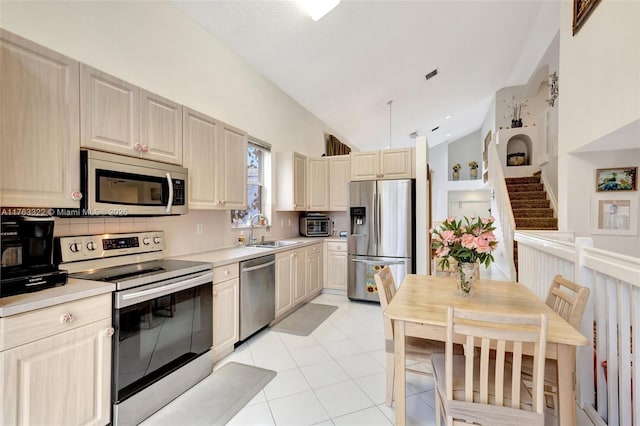 kitchen featuring visible vents, a sink, light countertops, vaulted ceiling, and appliances with stainless steel finishes