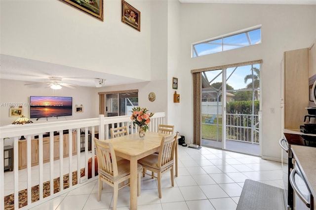 dining space with light tile patterned flooring, a high ceiling, and ceiling fan