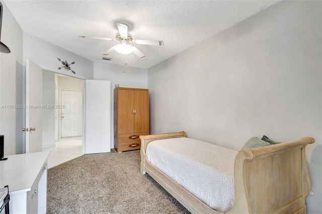 bedroom featuring light carpet, visible vents, a textured ceiling, and ceiling fan