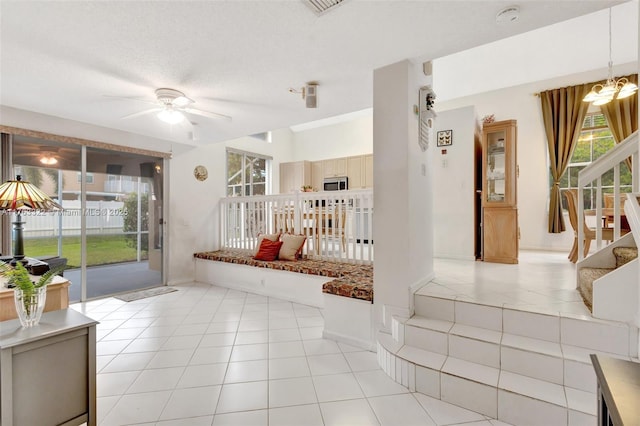 interior space with light tile patterned floors, stairway, a textured ceiling, and ceiling fan