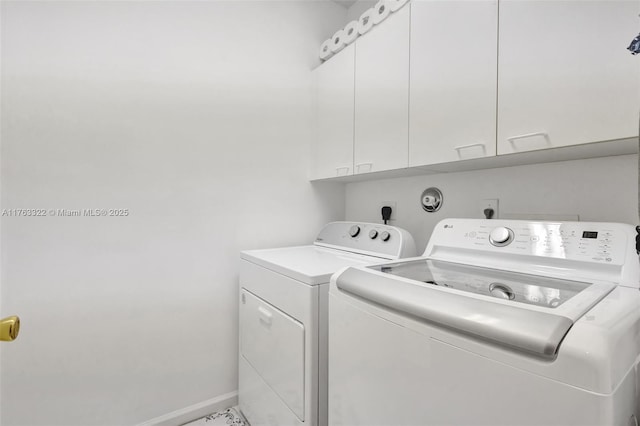 laundry area with washing machine and dryer, cabinet space, and baseboards