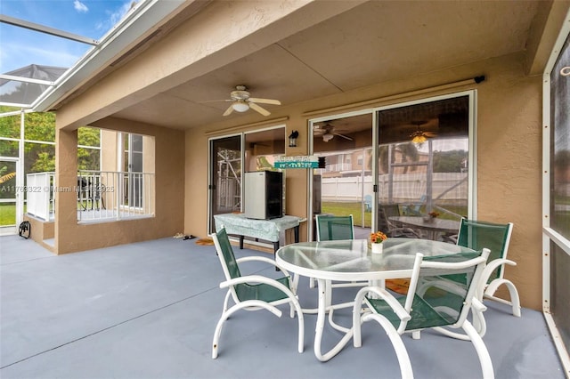 view of patio featuring a lanai, outdoor dining area, and ceiling fan