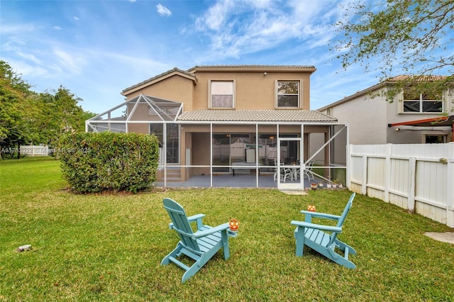 rear view of house with fence, an outdoor fire pit, a tile roof, a lawn, and a lanai