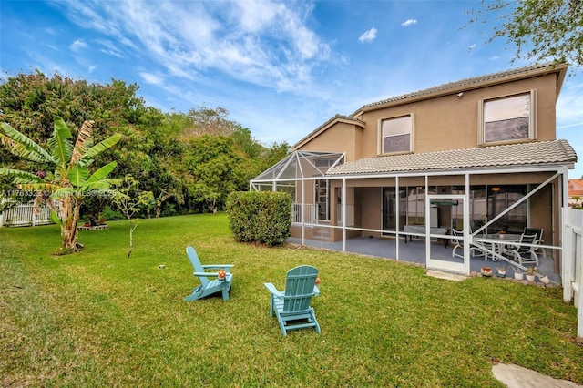 back of property with a tile roof, a lawn, glass enclosure, stucco siding, and a patio area