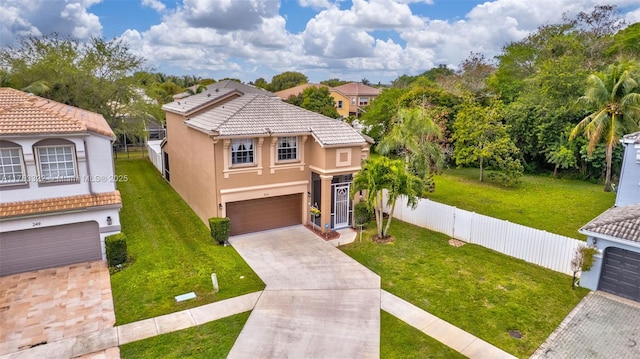 mediterranean / spanish-style home featuring stucco siding, concrete driveway, a front lawn, and fence