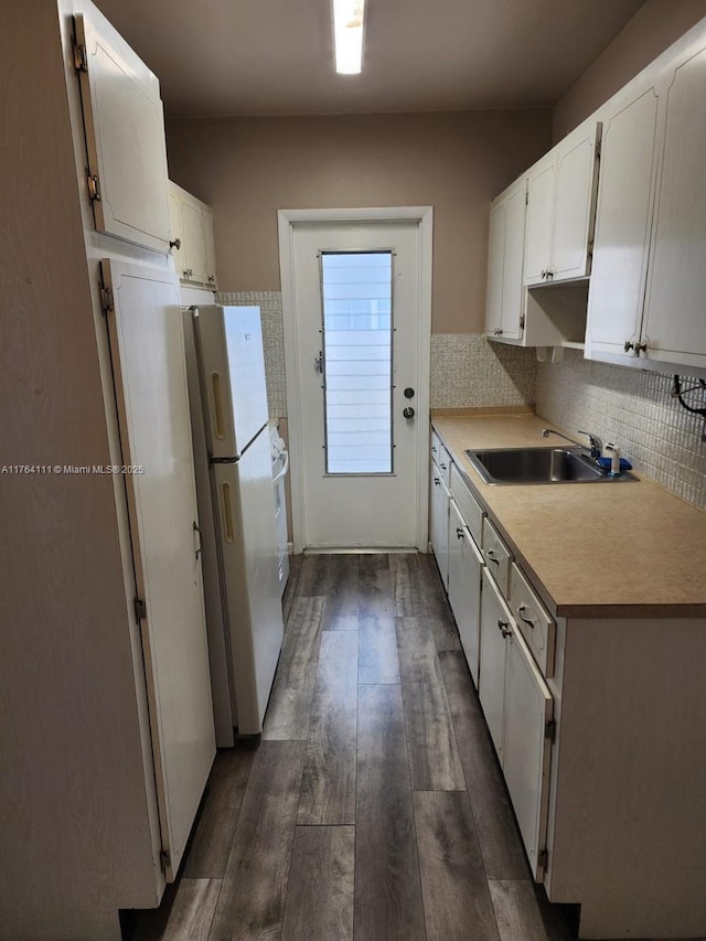 kitchen with dark wood finished floors, white cabinetry, freestanding refrigerator, and a sink