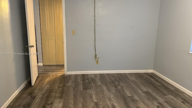 spare room featuring dark wood-type flooring and baseboards