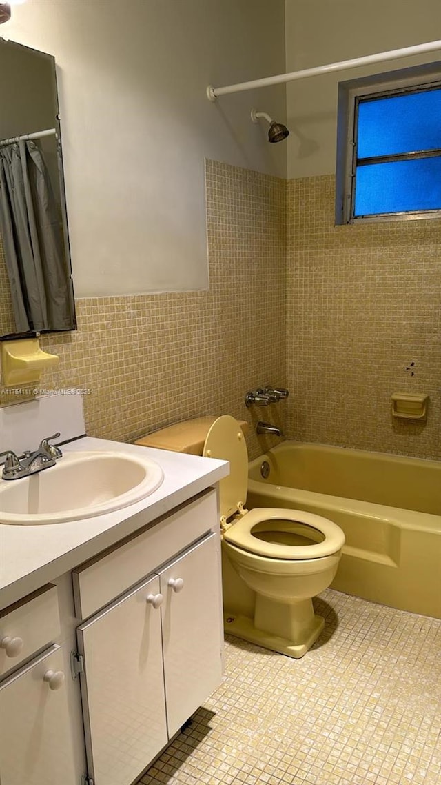 full bathroom with toilet, shower / bath combo, tile walls, wainscoting, and vanity