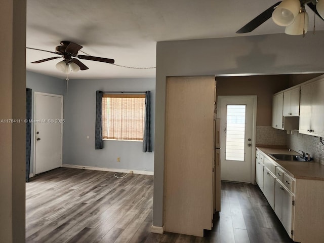 kitchen featuring backsplash, baseboards, ceiling fan, dark wood finished floors, and a sink