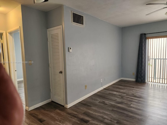 unfurnished room featuring dark wood finished floors, visible vents, baseboards, and a ceiling fan