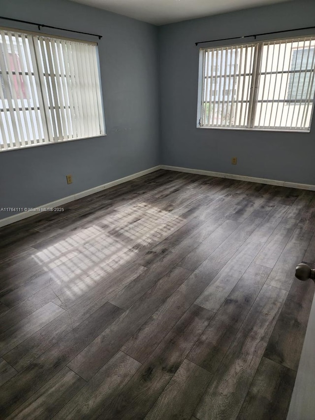 empty room with dark wood finished floors and baseboards