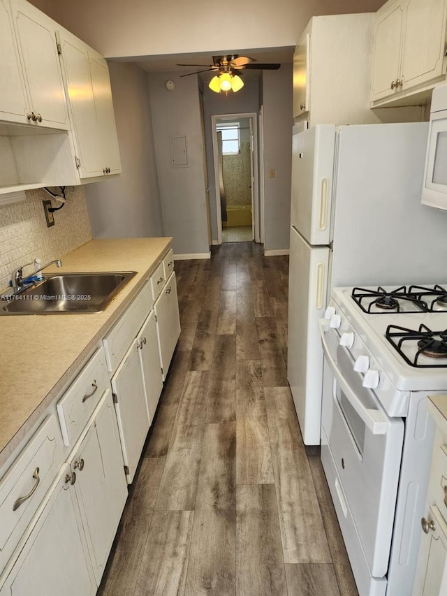 kitchen with white appliances, dark wood finished floors, a sink, light countertops, and white cabinetry