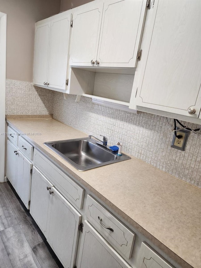 kitchen with a sink, light countertops, decorative backsplash, white cabinets, and open shelves